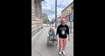 Ein junger Mann zieht einen Wagen hinter sich her, in dem eine junge Frau sitzt.