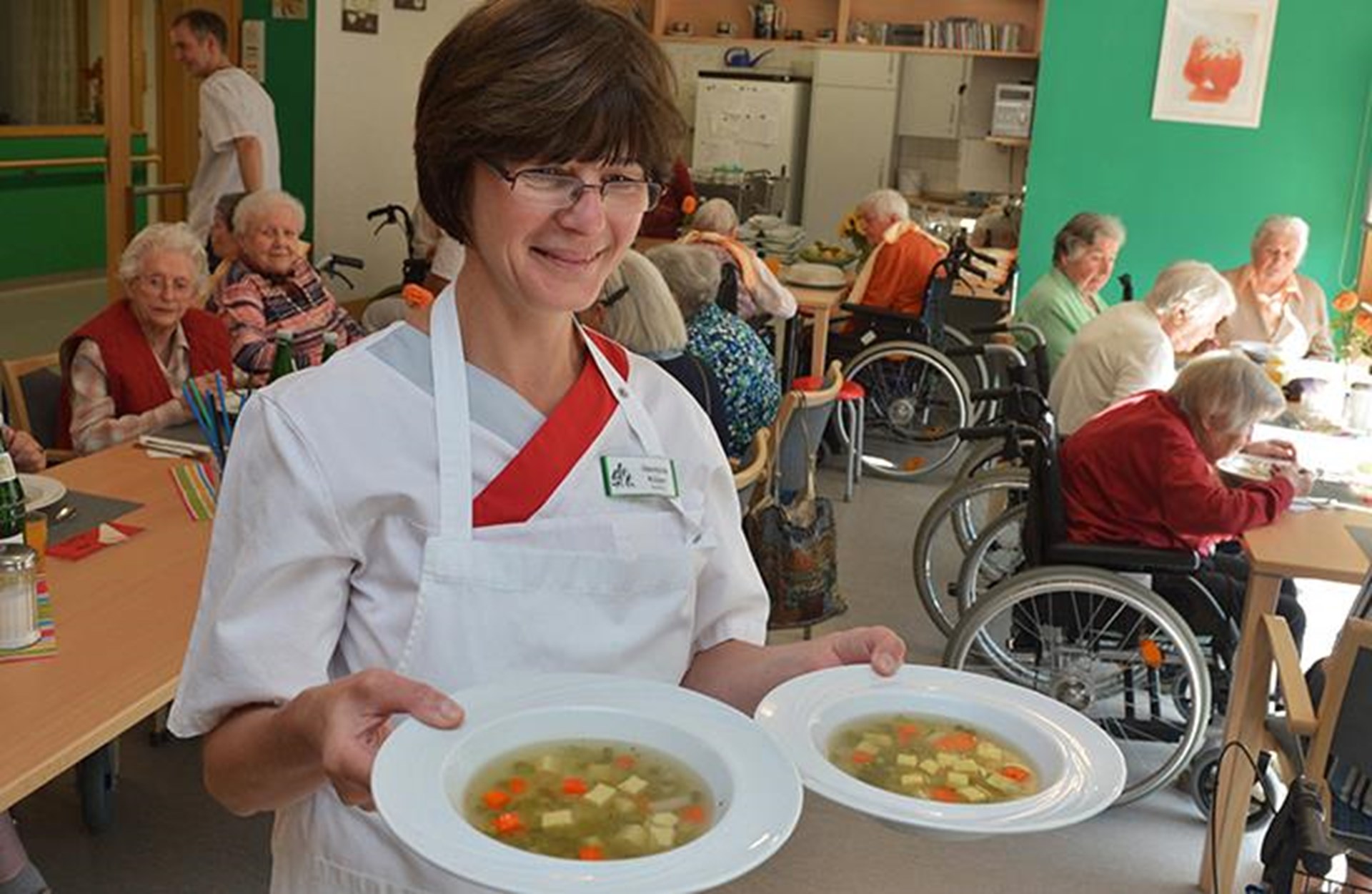 Eine Mitarbeiterin trägt zwei Teller Suppe